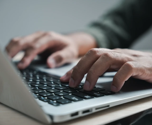 Close view of hands typing on a laptop keyboard